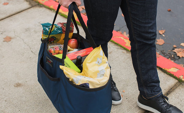 A person carrying a Monster Truck full of groceries via the padded carry handle.